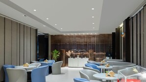 A modern interior with round tables and blue chairs, a reception area with a decorative plant, and a wall with vertical panels. - Jinjiang Inn Select (Tianjin)