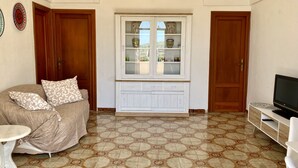 A living room with a sofa, a television, and a cabinet with glass doors. - DAMMUSO to REKALE (Rekhale)