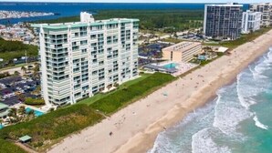 Un hotel de gran altura con varios pisos, una playa contigua al edificio y vistas al océano.