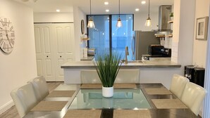 Un comedor moderno con una mesa de vidrio, sillas de cuero y un banco.