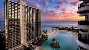 A high-rise hotel with multiple balconies overlooking a beach and a pool. - Hilton Hawaiian Village Lagoon Tower (Honolulu)