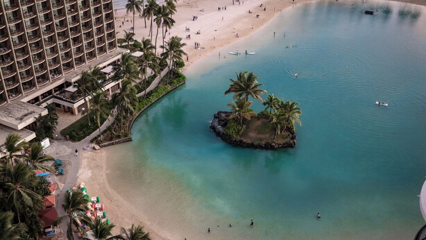 A hotel with multiple floors, a beach, clear blue water, and palm trees. - Hilton Hawaiian Village Lagoon Tower (Honolulu)