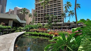 A hotel with a pool, palm trees, and a large building in the background. - Hilton Hawaiian Village Lagoon Tower (Honolulu)