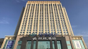 A tall hotel building with a modern facade, large windows, and a prominent sign for the Hyatt Hotel.