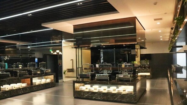 A modern hotel lobby with a reception desk, seating area, and a display of candles.