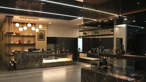 A modern reception area with marble counters, a central seating area, and a ceiling with linear lighting.