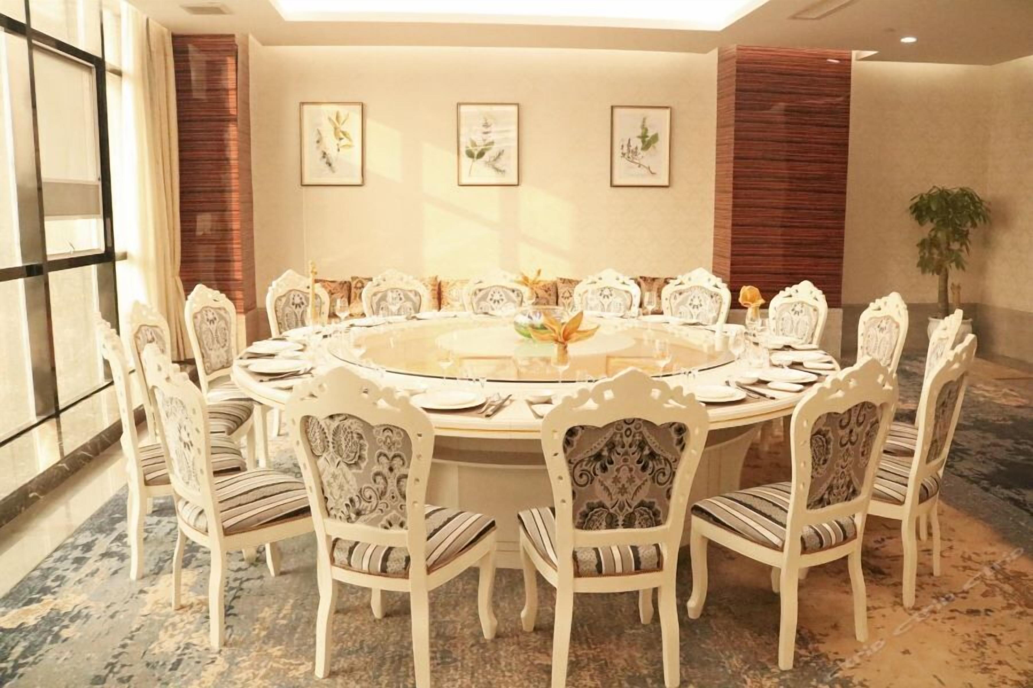 A round dining table with ornate chairs, surrounded by framed botanical artwork on the walls.