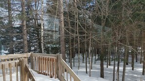 Un escalier en bois menant à une zone forestière enneigée, délimitée par une clôture.