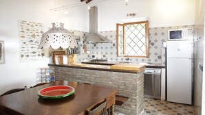 A kitchen with a wooden table, a microwave, a refrigerator, and a sink.