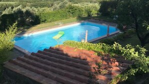 A swimming pool surrounded by lush greenery and hills in the background.