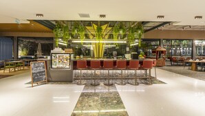 Un área de bar moderna con un arreglo central de plantas, taburetes y una pizarra.