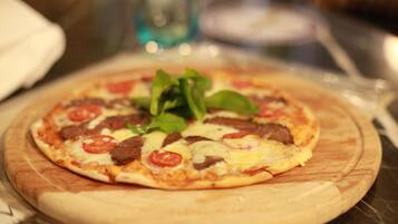 Una pizza sobre una tabla de madera con ingredientes como tomates, queso y vegetales verdes.