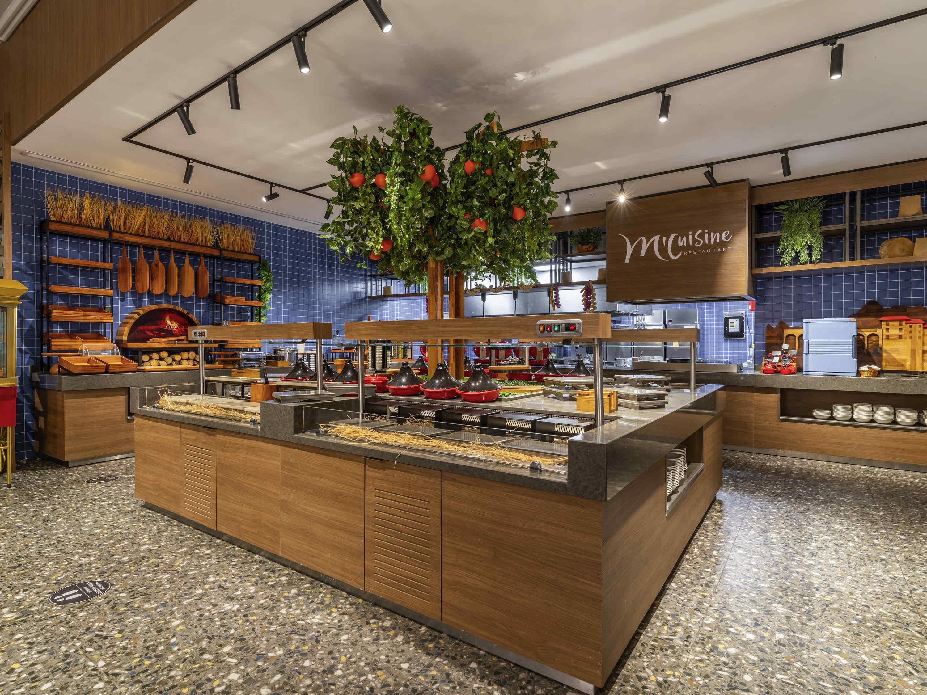 A buffet area with a central island, a blue tiled wall, and a sign for McCuisine Restaurant.