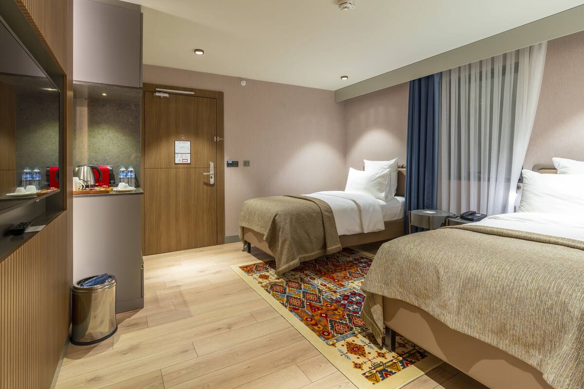 Ein Hotelzimmer mit Bett, Nachttisch und kleinem Schreibtisch mit Mülleimer.