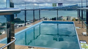 Una piscina en la azotea con vista despejada a un puente y al paisaje urbano de fondo.