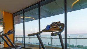 Un gimnasio con cintas de correr y vista al mar.