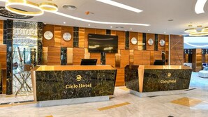 Zona de recepción de un hotel con suelo de mármol, paneles de madera y un diseño moderno.