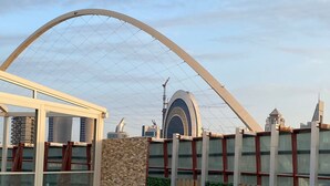 Una piscina con vistas despejadas a la arquitectura circundante, incluyendo una estructura de arco característica y un edificio moderno con fachada de vidrio.