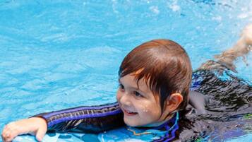 Un enfant dans une piscine, portant un maillot de bain bleu et violet.