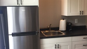 A kitchen with white cabinets, a stainless steel refrigerator, a sink, and a coffee maker. - Lauren's Loft in Historic Downtown Pleasant Hill (Pleasant Hill)