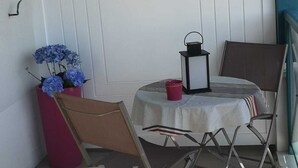 Un pequeño espacio al aire libre con una mesa, sillas, un farol y una planta en maceta.
