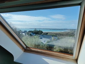 A skylight with a view of a coastal landscape, including houses and cliffs.