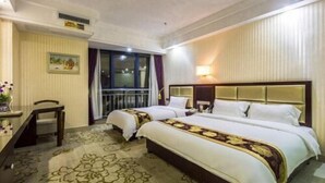 Een hotelkamer met twee bedden, een bureau en een groot raam.