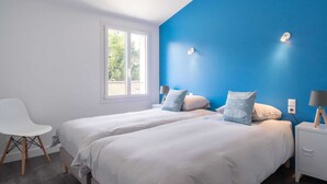 Une chambre avec deux lits, une fenêtre et une chaise.