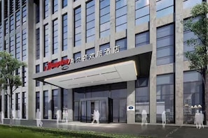 A modern hotel with a prominent sign, large windows, and a covered entrance. - Hampton By Hilton Nanjing South Railway Station (Nanjing)