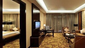 A hotel room with a bed, a television, a desk with a computer, a chair, and a sofa. - Best Western Ridong Garden Hotel (Xiamen)