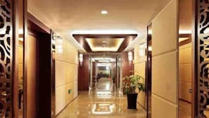 A hotel corridor with a polished floor, decorative panels, and a potted plant. - Best Western Ridong Garden Hotel (Xiamen)