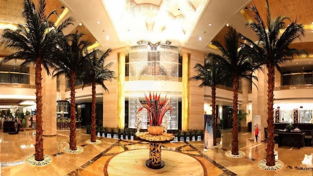 A spacious lobby with a central fountain, palm trees, and a high ceiling with chandeliers. - Best Western Ridong Garden Hotel (Xiamen)