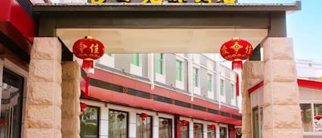 A building with a sign in yellow characters, stone pillars, and red lanterns.