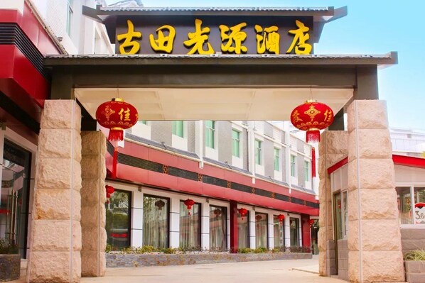 A building with a sign in yellow characters, stone pillars, and red lanterns.