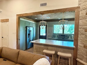Una cocina moderna con una isla central, taburetes de bar y una pared de acento de piedra.