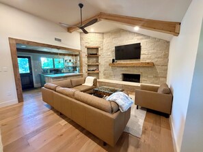 Una sala de estar moderna con chimenea de piedra, un sofá grande y un televisor montado arriba.