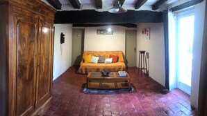 Een gezellige kamer met een houten kledingkast, een bank met kussens, een bijzettafeltje met een vaas en een raam met uitzicht.