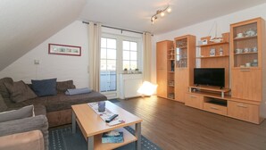 Una sala de estar acogedora con un sofá, una mesa de centro y armarios de madera con puertas de vidrio.