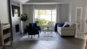 Un salon spacieux avec une cheminée, un canapé, une table basse et un téléviseur fixé au mur.