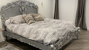Une chambre avec un grand lit, un plancher en bois et une fenêtre avec des rideaux.