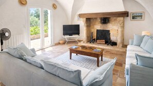 A spacious living room with a stone fireplace, a television, and a sofa. - nice villa with with pool and seaview (agay)
