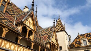 A historic building with a distinctive roof featuring geometric patterns and pointed gables.