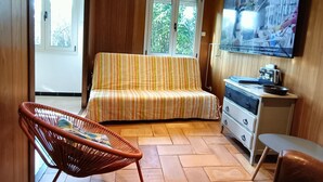 A cozy room with a striped sofa, a wicker chair, a TV, and a wooden cabinet.