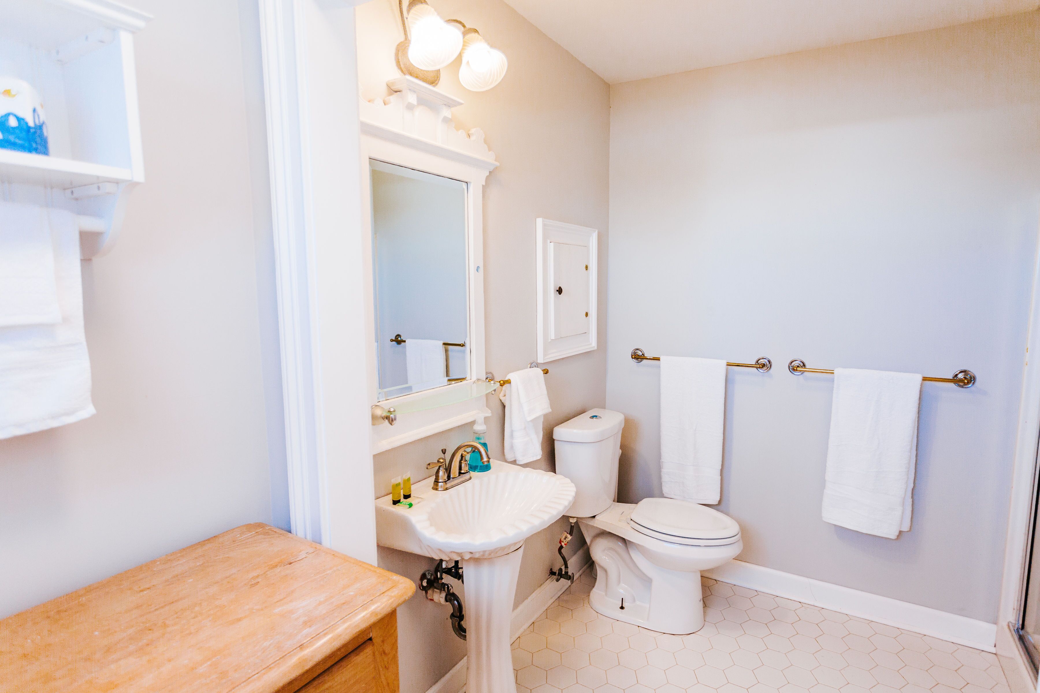 A bathroom with a white sink, toilet, and a mirror above the sink. There are two towels hanging on a towel rack.