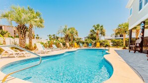 A swimming pool with lounge chairs, palm trees, and a building in the background. - Palazzo 360 5bdr/5 bath with a heated pool sleeps 18 (Murrells Inlet)