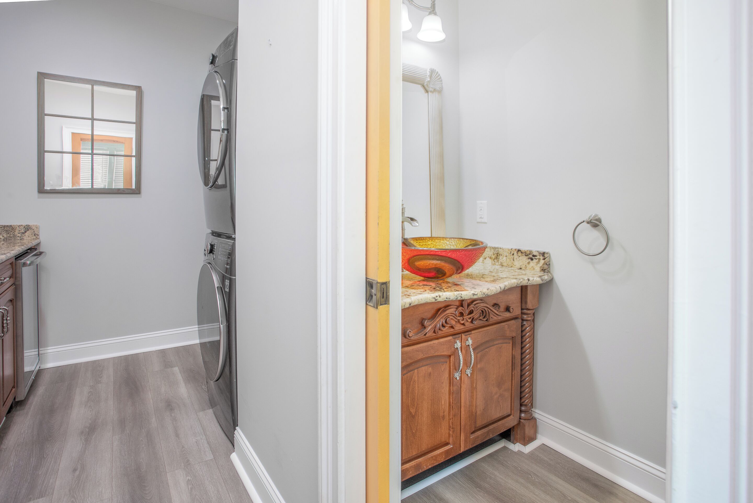A bathroom with a sink, mirror, and towel ring.