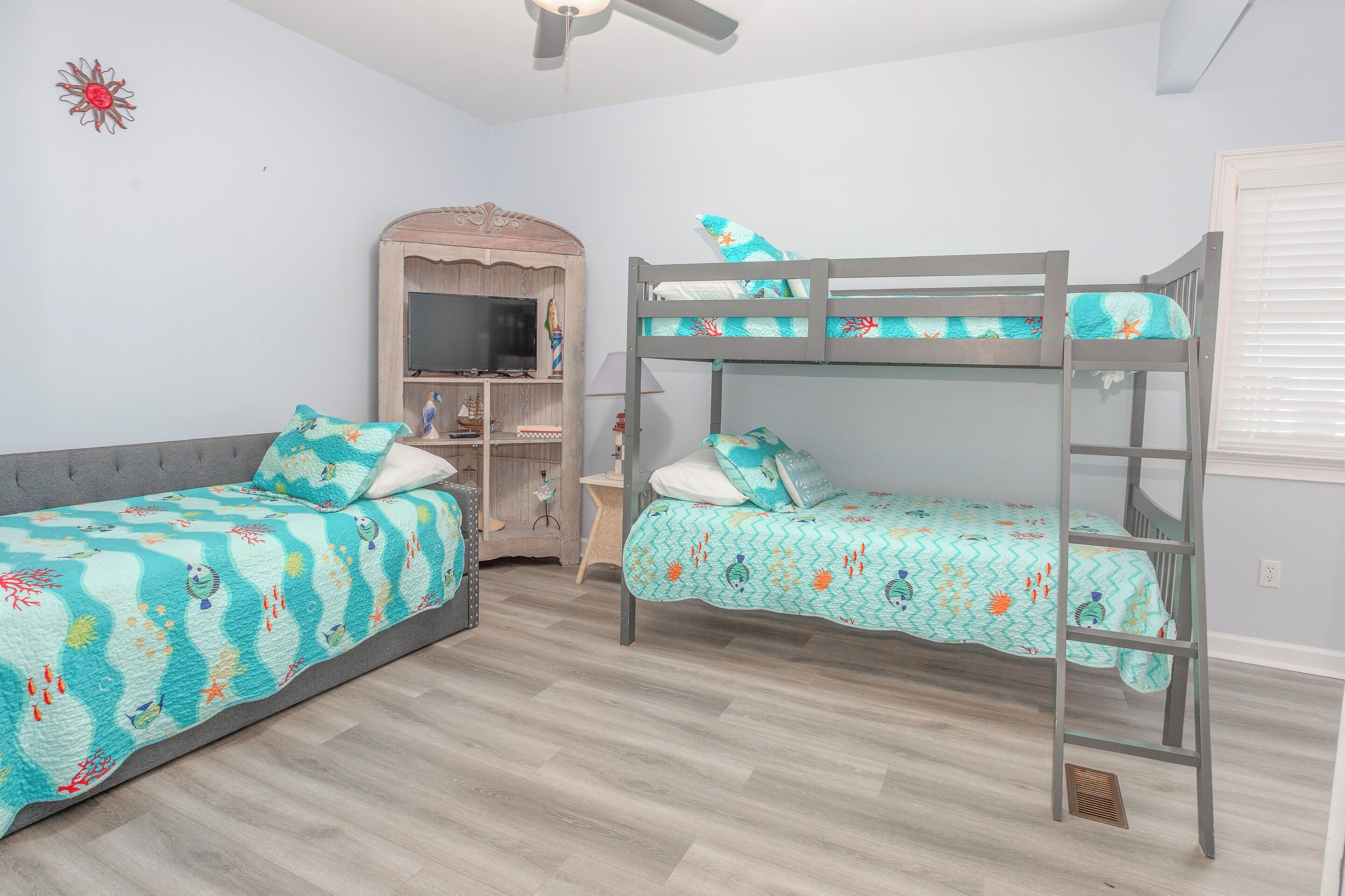 A room with bunk beds, a television, a small desk, and a decorative wall piece.