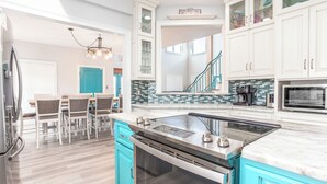 A modern kitchen with a central island, built-in appliances, and a dining area with chairs. - Palazzo 360 5bdr/5 bath with a heated pool sleeps 18 (Murrells Inlet)