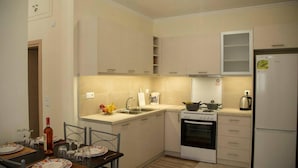 Une cuisine compacte équipée d’une cuisinière, d’un évier et d’un réfrigérateur. On y trouve une table à manger, mise avec des assiettes et des verres.