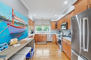 A modern kitchen with wooden cabinets, stainless steel appliances, and a large window.